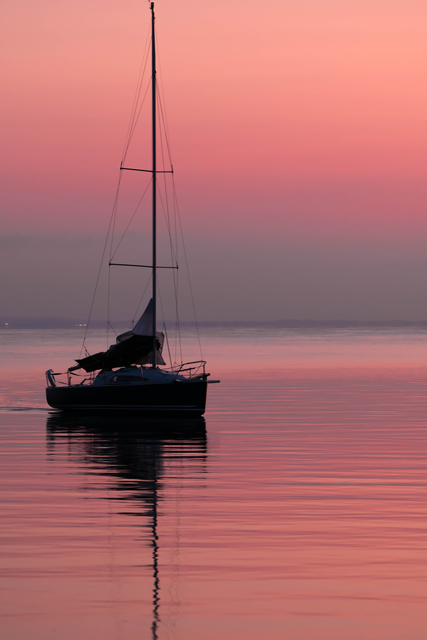 Sailboat silhouette on calm pink sunset