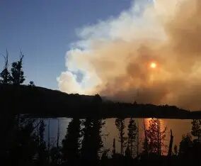 Wildfire smoke and sun reflected on lake