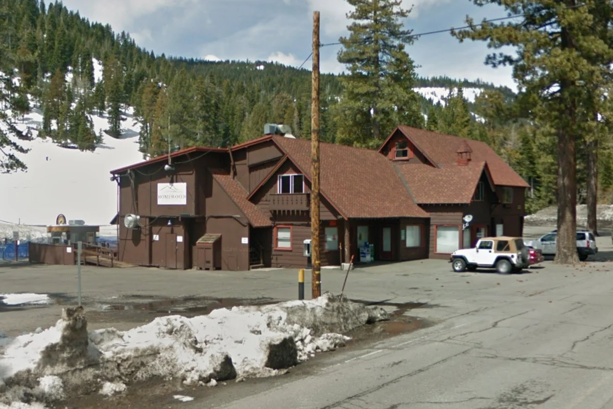 Brown wooden mountain lodge by snowy road with jeep